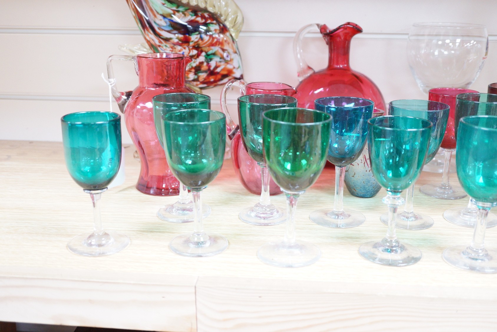 A quantity of cranberry glass, together with other coloured glassware and a Murano style fish ornament